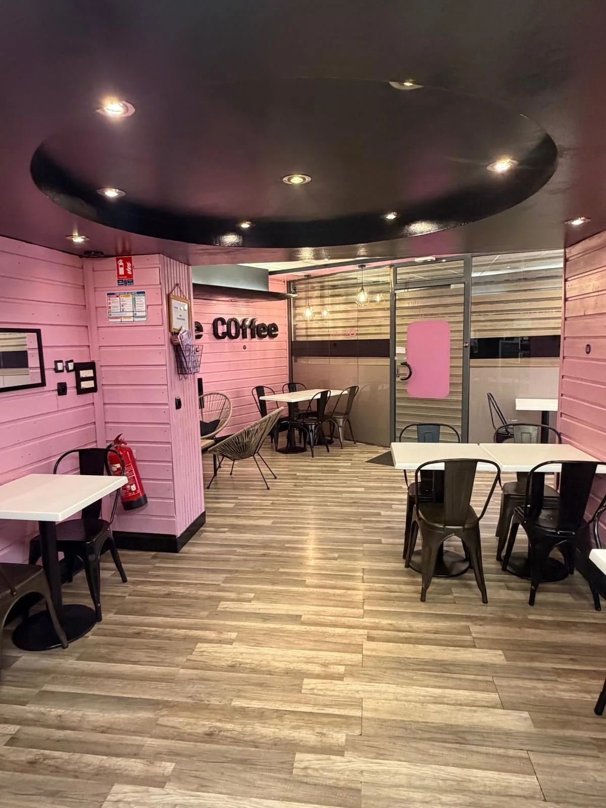 Salle chaleureuse d'Ice Coffee avec tables et décoration rose